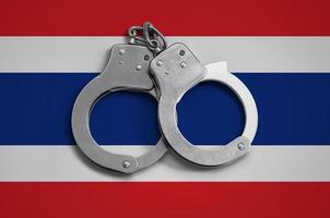 Thailand vlag en Politie handboeien. de concept van naleving van de wet in de land en bescherming van misdrijf foto