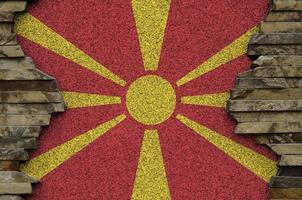 Macedonië vlag afgebeeld in verf kleuren Aan oud steen muur detailopname. getextureerde banier Aan rots muur achtergrond foto