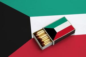 Koeweit vlag is getoond in een Open luciferdoosje, welke is gevulde met wedstrijden en leugens Aan een groot vlag foto