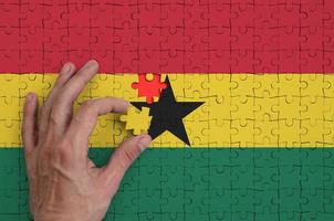 Ghana vlag is afgebeeld Aan een puzzel, welke de man's hand- voltooit naar vouwen foto