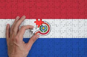 Paraguay vlag is afgebeeld Aan een puzzel, welke de man's hand- voltooit naar vouwen foto
