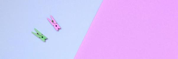 twee gekleurde houten haringen liggen Aan structuur achtergrond van mode pastel paars en roze kleuren papier foto