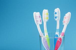 kleurrijk tandenborstels in een glas Aan een blauw achtergrond. foto