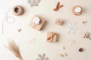 Kerstmis decoraties met verpakking cadeaus in ambacht papier en bloemen Aan beige achtergrond. vlak leggen, kopiëren ruimte foto