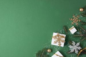 Kerstmis decoraties met verpakking cadeaus en Kerstmis boom Aan groen achtergrond. vlak leggen, kopiëren ruimte foto