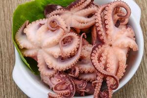 gemarineerde octopus in een kom op houten achtergrond foto