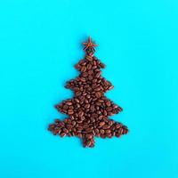 Kerstmis boom gemaakt van koffie bonen en versierd anijs ster Aan een blauw achtergrond, top visie. foto