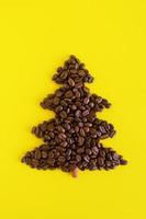 winter samenstelling met Kerstmis boom gemaakt door koffie bonen en versierd kaneel stok Aan een geel achtergrond, vlak leggen. groet kaart voor nieuw jaar met kopiëren ruimte. foto