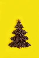 winter samenstelling met Kerstmis boom gemaakt door koffie bonen en versierd anijs ster en kaneel stok Aan een geel achtergrond, vlak leggen. groet kaart voor nieuw jaar met kopiëren ruimte. foto