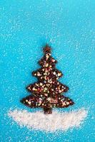 Kerstmis boom gemaakt van koffie bonen en versierd anijs ster, veelkleurig culinaire sprenkeling en kokosnoot chips Aan een blauw achtergrond, top visie. foto