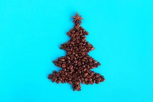 Kerstmis boom gemaakt van koffie bonen en versierd anijs ster Aan een blauw achtergrond, top visie. foto