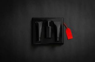 een zwart doos van parfum met blanco rood prijs label Aan zwart achtergrond. zwart vrijdag concept. foto
