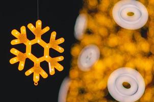 gedeeltelijk focus van neon lichten sneeuw vlok Kerstmis ornament met wazig chirstmas boom achtergrond. foto