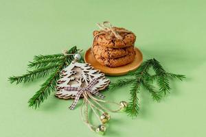 Kerstmis samenstelling met chocola chips koekjes Aan groen papier met Spar boom takken en houten speelgoed. feestelijk groet kaart. foto