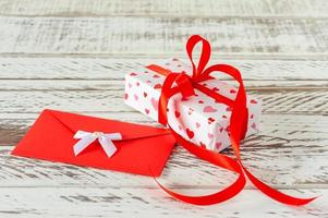 valentijnsdag dag geschenk doos met envelop met liefde brief, papier harten Aan houten achtergrond. groet kaart voor valentijnsdag dag of verjaardag. foto