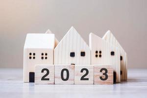 2023 gelukkig nieuw jaar met huis model- Aan tafel houten achtergrond. bankieren, echt landgoed, investering, financieel, spaargeld en nieuw jaar resolutie concepten foto