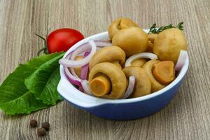 ingelegde champignon in een kom op houten achtergrond foto