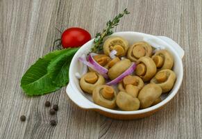 ingelegde champignon in een kom op houten achtergrond foto