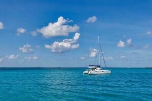 luxe jacht in Open wateren met mooi wolken. catamaran wit zeilboot in tropisch oceaan lagune, zee horizon onder zonnig horizon. idyllisch buitenshuis sport en reizen recreatie landschap, zeegezicht