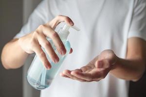 Mens gebruik makend van alcohol ontsmettingsmiddel gel wrijven voor schoonmaak hand- covid-19 corona virus het voorkomen concept foto