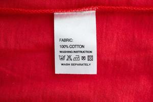 wit wasserij zorg het wassen instructies kleren etiket Aan rood katoen overhemd foto
