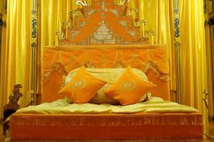 istana verminken, medan noorden sumatera, Indonesië - oktober 23, 2021, oranje bed met kussens en versierd met gouden gordijnen foto