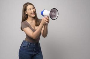 jong glimlachen vrouw Holding megafoon over- wit achtergrond studio. foto