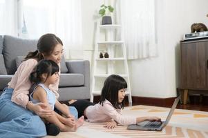 Aziatisch familie met kinderen gebruik makend van laptop computer Bij huis foto