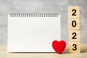 2023 kubussen met rood hart vorm en leeg notitieboekje Aan tafel voor uw tekst. nieuw jaar, oplossing, doel, plan, Gezondheid, liefde en gelukkig Valentijn dag concept foto