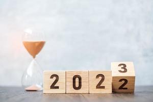 omdraaien blok 2022 naar 2023 tekst met zandloper Aan tafel. oplossing, tijd, plan, doel, motivatie, opnieuw opstarten, countdown en nieuw jaar vakantie concepten foto