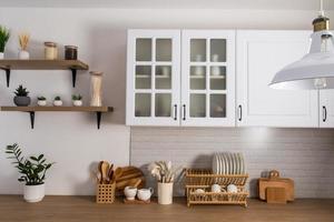 een deel van de interieur van een wit modern keuken met kasten met berijpt glas, een steen wit muur en een houten aanrecht. keuken apparatuur. foto