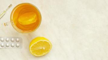 top visie, een kop van thee met een plak van de citroen, a voor de helft van de citroen, pillen en thermometer, copyspace foto