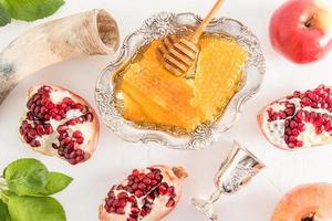 een groot zilver kom van honing en traditioneel producten vieren de Joods nieuw jaar van roshhashan Aan een wit achtergrond. top visie. foto