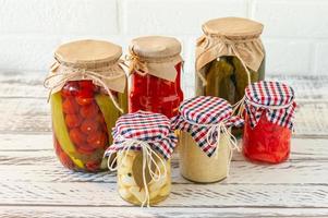 gemarineerd augurken verscheidenheid bewaren potten. eigengemaakt tomaten, komkommers, knoflook, gember en mierikswortel augurken. gefermenteerd voedsel. foto