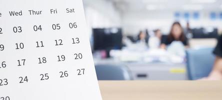 wit papier bureau kalender Aan hout tafel top met wazig kantoor interieur achtergrond foto