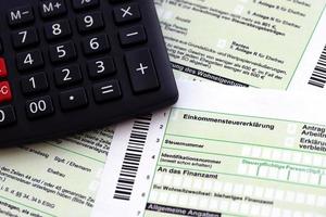 Duitse jaar- inkomen belasting terugkeer verklaring en rekenmachine leugens Aan accountant tafel dichtbij omhoog. de concept van belasting betalen periode in Duitsland foto