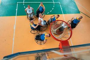 gehandicapt oorlog of werk veteranen gemengd ras en leeftijd basketbal teams in rolstoelen spelen een opleiding bij elkaar passen in een sport- Sportschool hal. gehandicapten mensen revalidatie en inclusie concept. foto