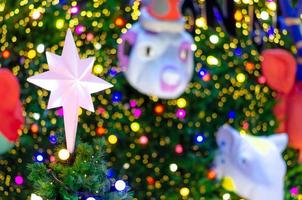 ster ornament zet Aan top van Kerstmis boom voor vakantie decoratie met kleurrijk lichten Aan achtergrond. foto