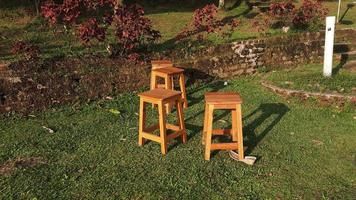 een weinig houten stoelen in de groen tuin met de avond zon schijnend 01 foto