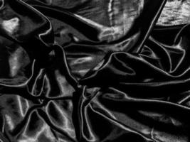 zwart satijn structuur achtergrond met vloeistof Golf of golvend vouwen. behang ontwerp foto