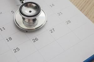 stethoscoop met kalender bladzijde datum Aan hout tafel achtergrond dokter afspraak medisch concept foto