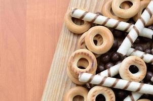 krokant buisjes, chocola smelten ballen en bagels liggen Aan een houten oppervlak. mengen van divers snoepgoed foto