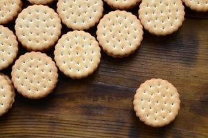 een ronde belegd broodje koekje met kokosnoot vulling leugens in groot hoeveelheden Aan een bruin houten oppervlak. foto van eetbaar behandelt Aan een houten achtergrond met kopiëren ruimte