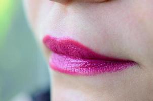 dichtbij omhoog schot van vrouw lippen met glanzend fuchsia lippenstift foto