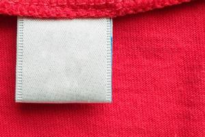 wit blanco wasserij zorg kleren etiket Aan rood katoen overhemd achtergrond foto