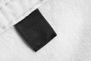 zwart blanco wasserij zorg kleren etiket Aan wit katoen overhemd achtergrond foto