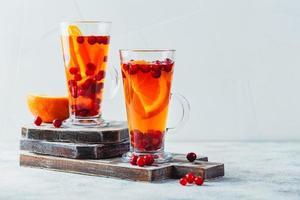 oranje en veenbes drankjes met oranje plakjes en specerijen. heet drankjes voor winter en Kerstmis foto