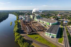 antenne panoramisch visie Aan rook pijpen van een houtbewerking fabriek Aan de bank van een breed rivier- foto