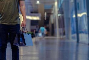 Mens Holding boodschappen doen Tassen met boodschappen doen winkelcentrum achtergrond. zwart vrijdag boodschappen doen uitverkoop concept. foto