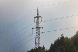 hoog Spanning pyloon bovenstaand de bossen van de Alpen foto